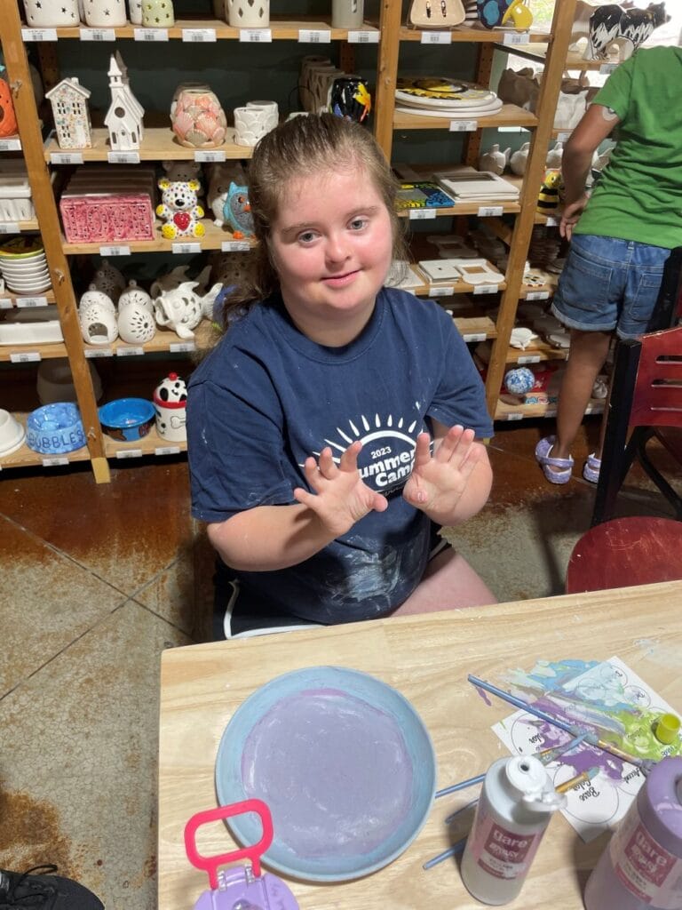 Hannah proudly shows off her painted pottery.
