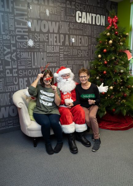 two volunteers sitting next to Santa and using Christmas props