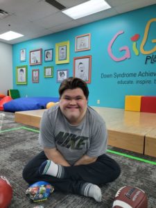 Boy with Down syndrome smiling and wearing a Nike t-shirt with a colorful background