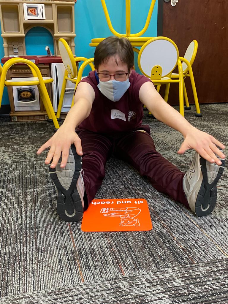girl wearing a mask seated and touching her toes