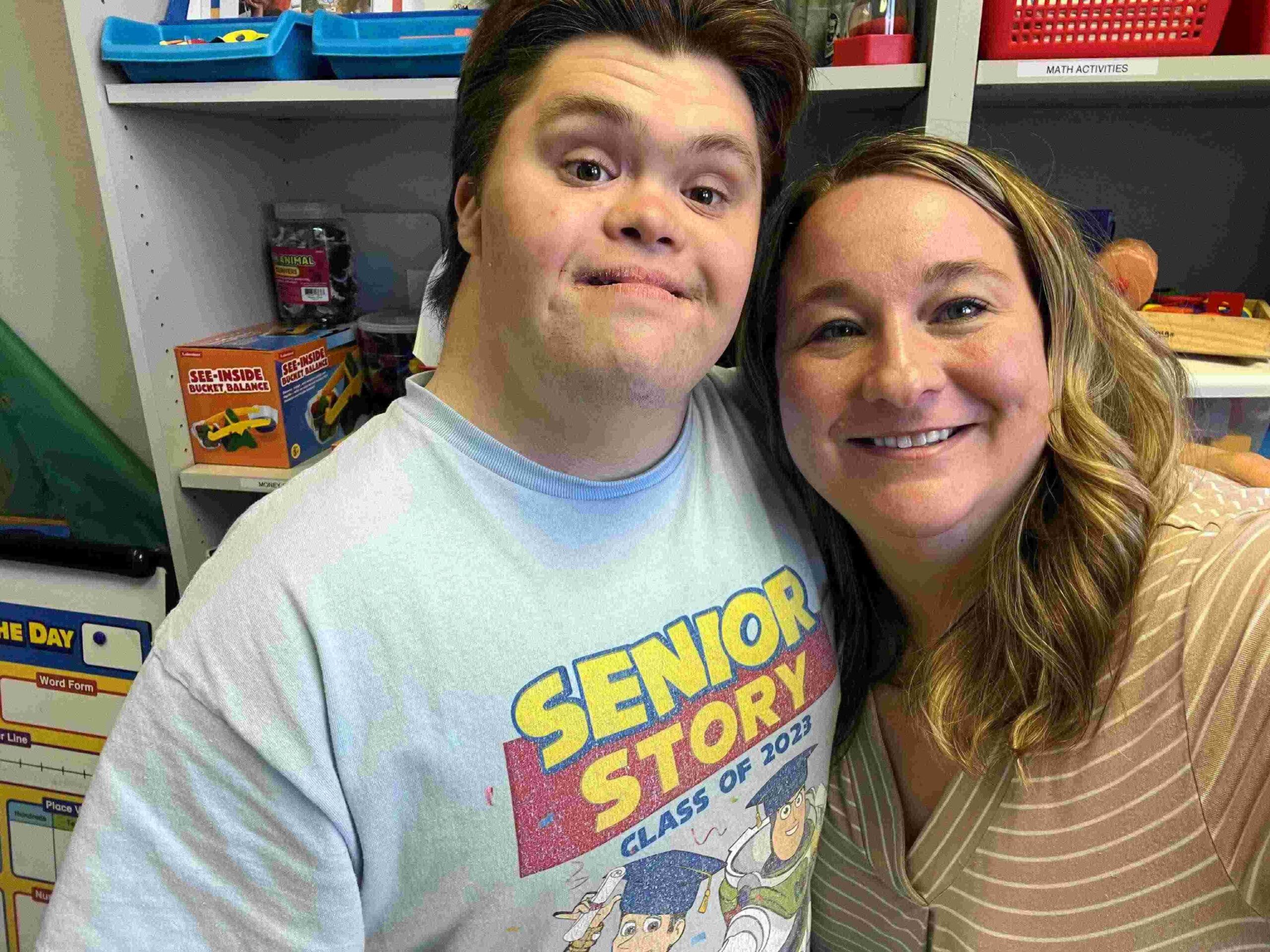 Boy with down syndrome and his female tutor smiling