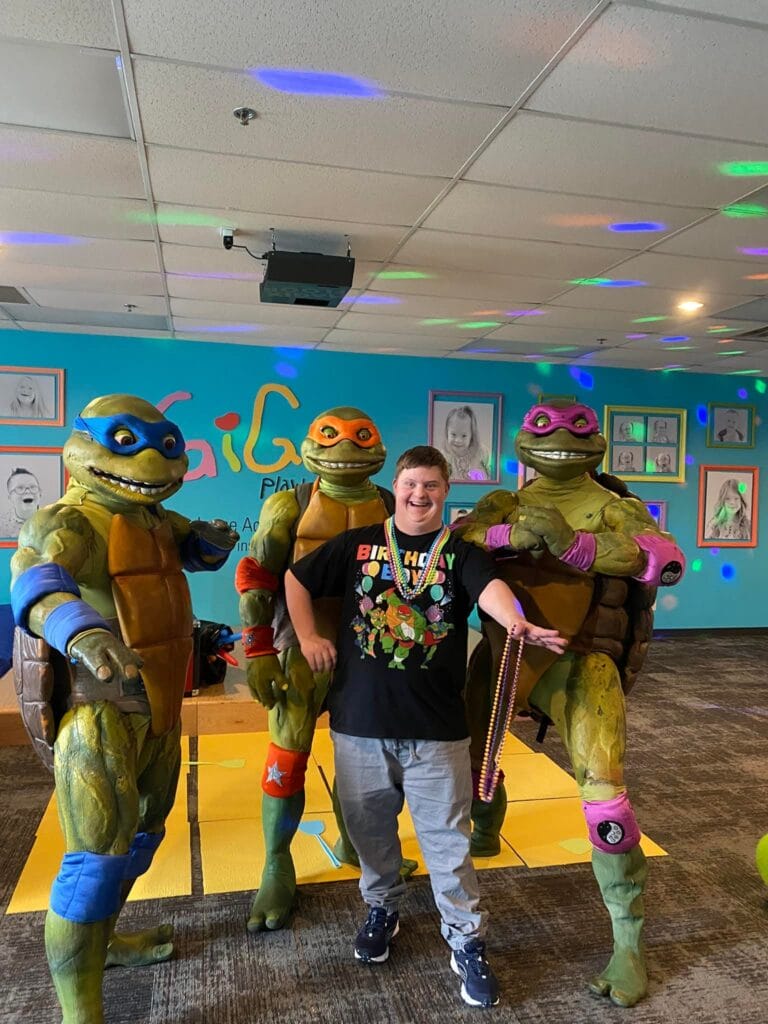 Boy in black t-shirt surrounded by the Teenage Mutant Ninja Turtles in costume