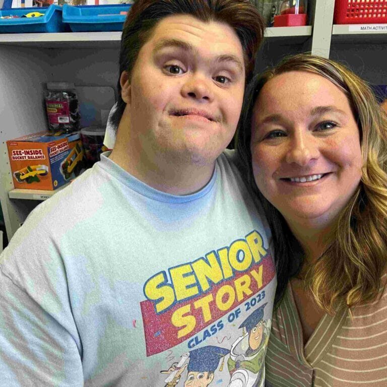 Boy with down syndrome and his female tutor smiling