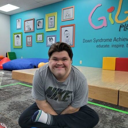 Boy with Down syndrome smiling and wearing a Nike t-shirt with a colorful background