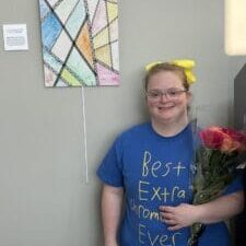 A female with bouquet of flowers standing in front of painting.