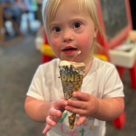 Toddler who has Down syndrome holding an ice cream cone