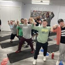 Participants from GiGiFIT Teen &amp; Adult strike strong and confident poses during a workout session at All Star Fitness. Smiling and flexing their muscles, the group radiates energy and pride in their progress. 