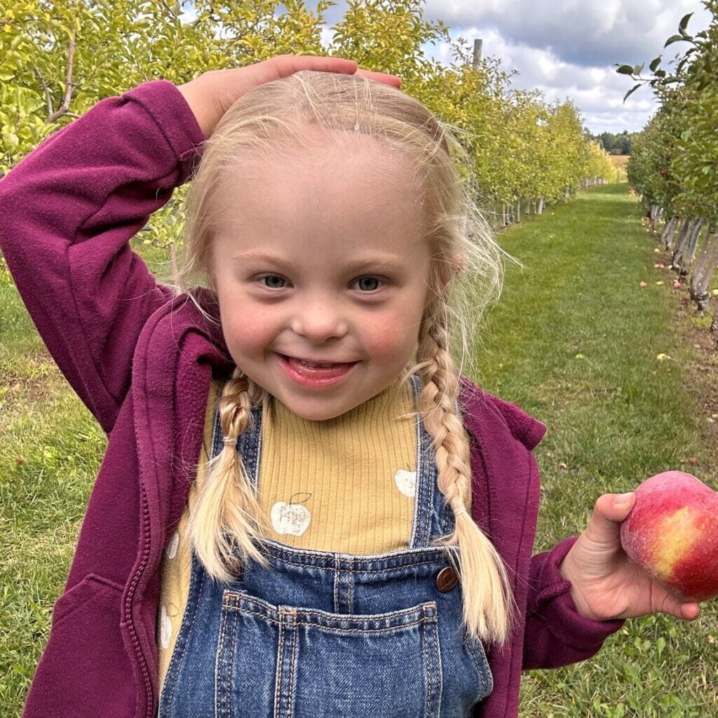 Emme is a girl with Down syndrome shown at the apple orchard