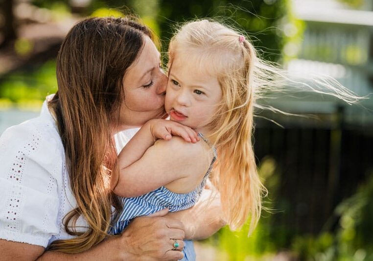 Little girl being kissed by her mom