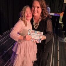 Individual with Down syndrome presenting tutor award.