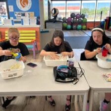 three girls sitting at a table making sand as a summer activity