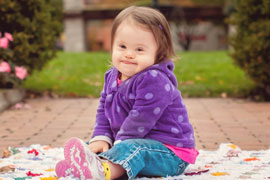 baby girl with Down syndrome smirking 