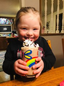Little girl with Down syndrome drinking a milkshake smiling
