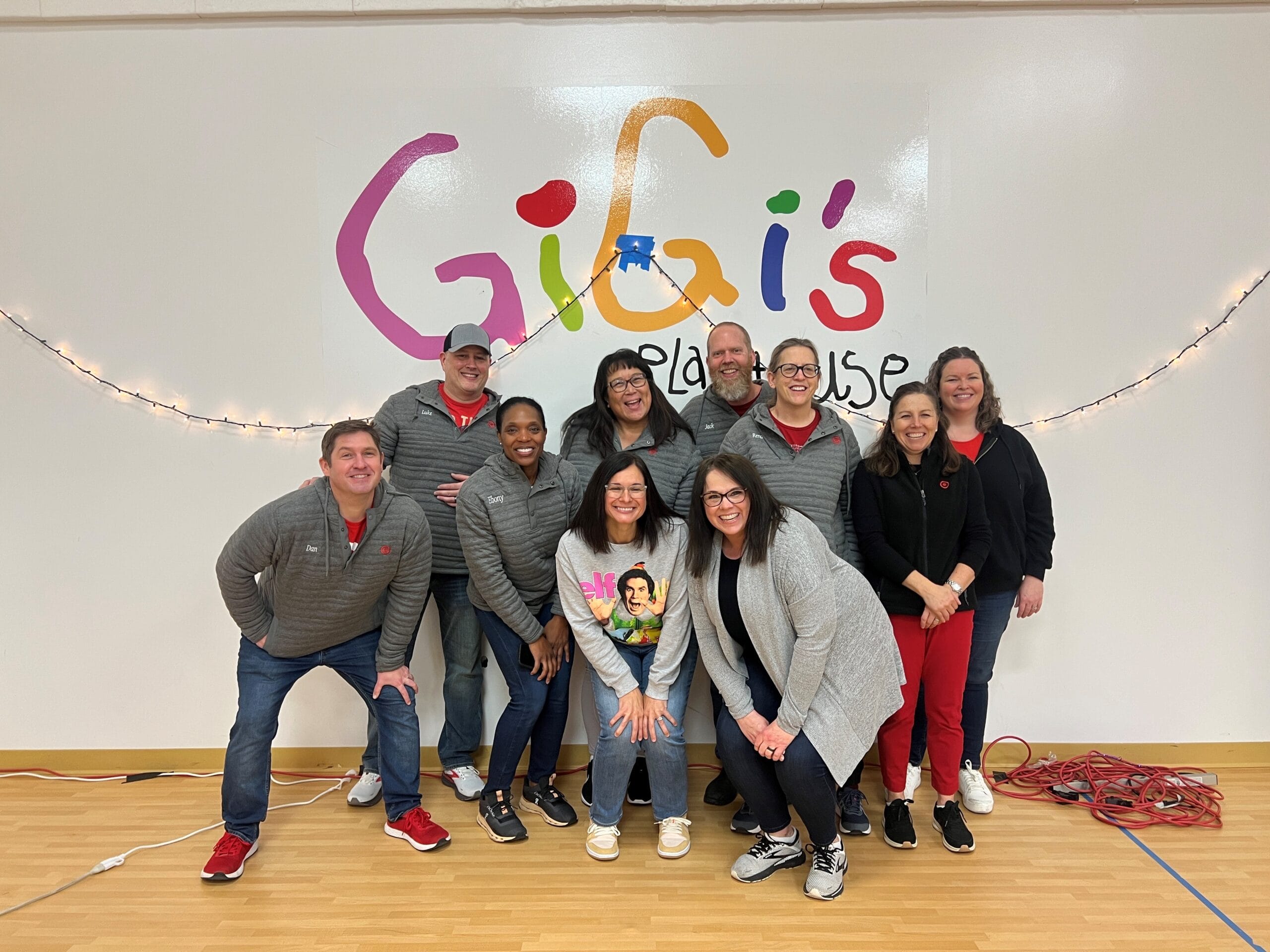Target Team standing in front of GiGi's Logo in gym.