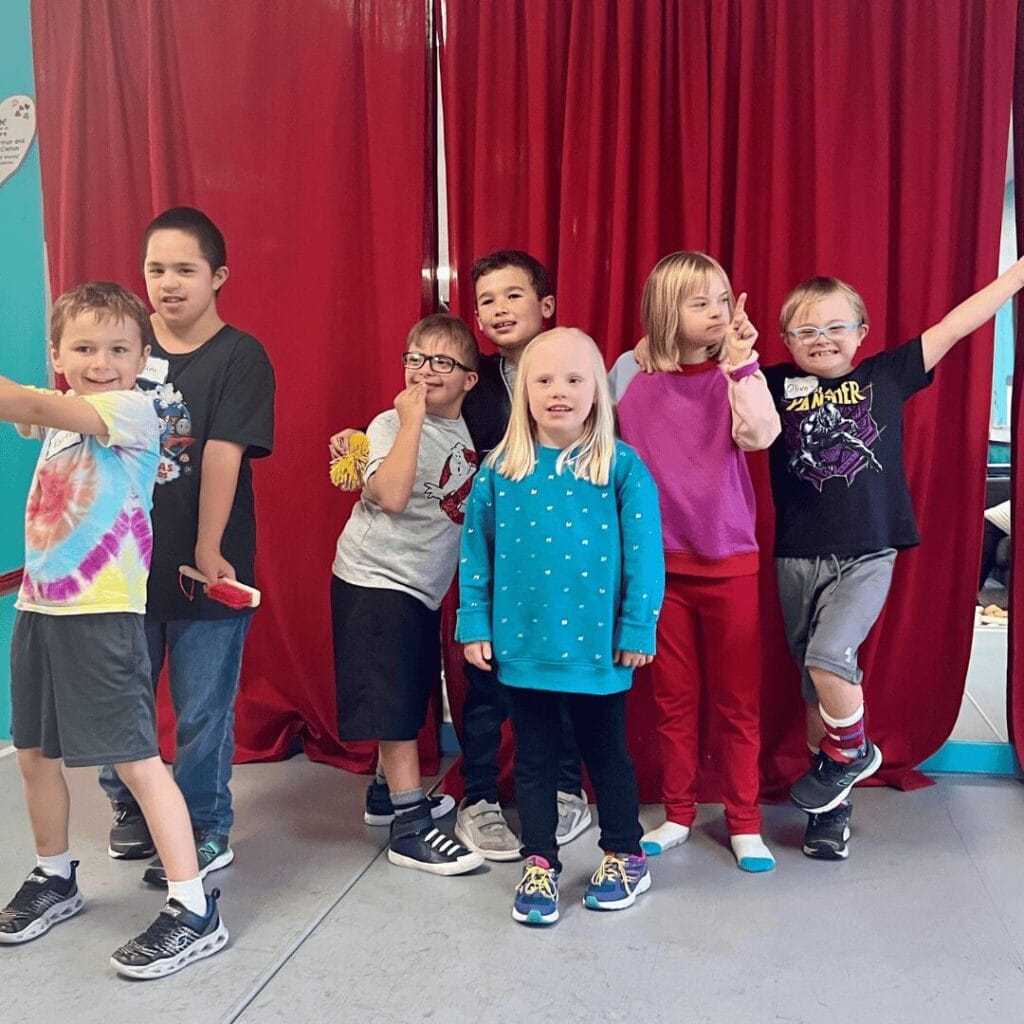 A group of friends standing in front of a mirror and curtain posing for a photo.