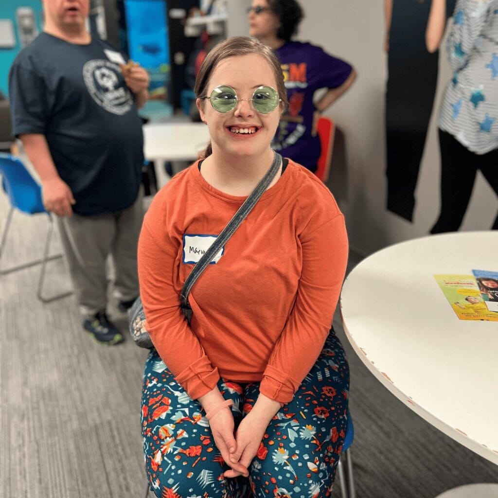 An adult women in an orange shirt smiling for a photo.