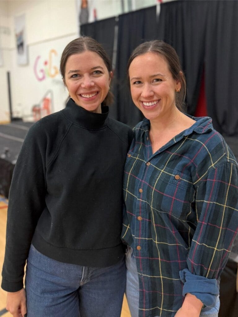 Two Sisters standing in front of stage smiling.