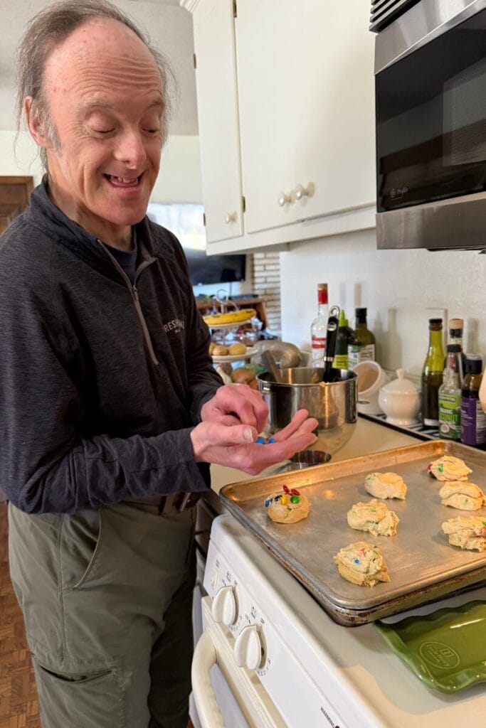 John holding a ball of cookie dough adding M&Ms.