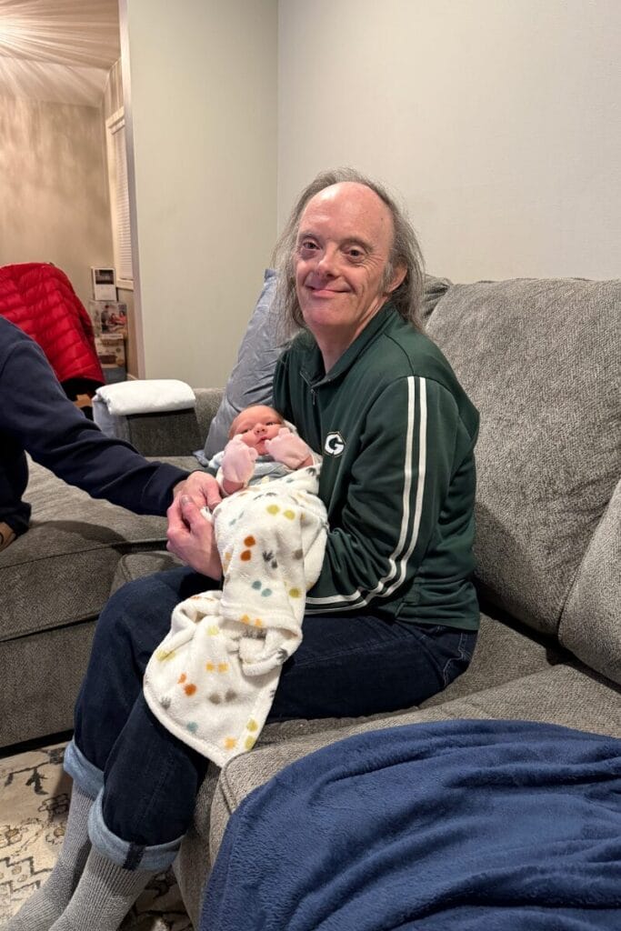 John wearing a Green Bay Packers shirt holding his new born great niece.