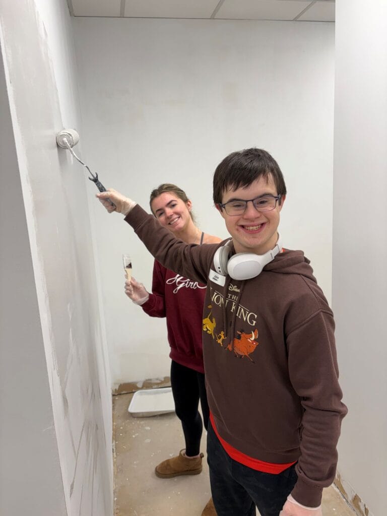 A smiling young woman and teen painting walls.