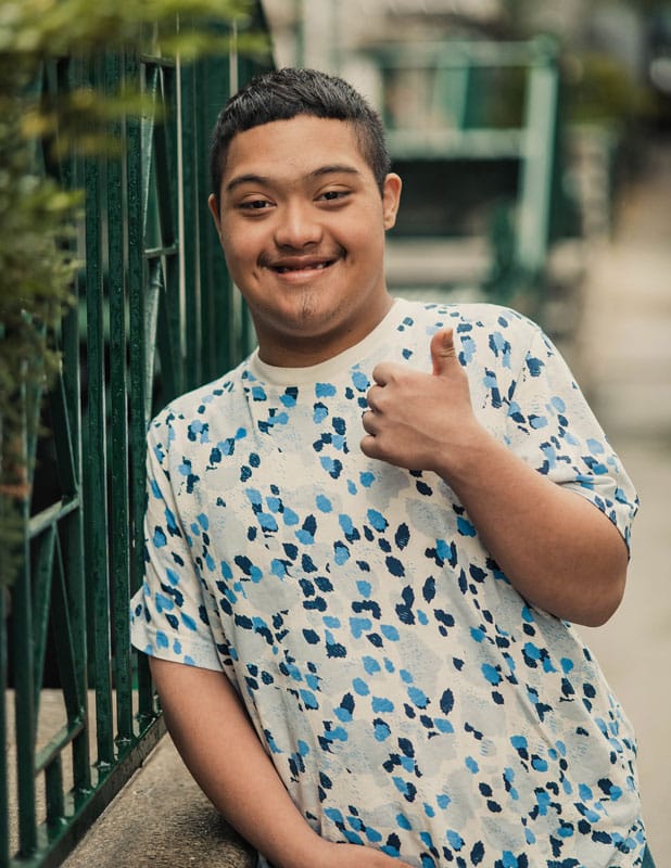 young adult with Down syndrome giving a thumbs up