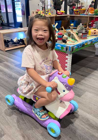 girl on a toy smiling