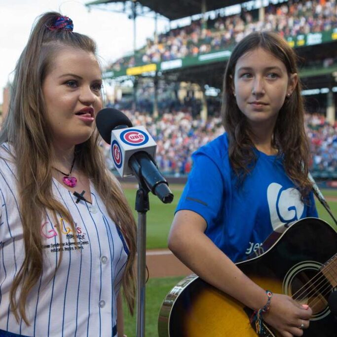 GiGi Gianni sings National Anthem at Wrigley Field. To the right is Abby, from School of Rock in Barrington, playing the guitar.